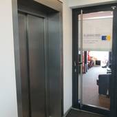 Eingang neben Aufzug, Glastür mit Streifen
