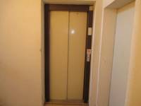  geschlossener Aufzug mit deunklem Rahmen, rechts daneben weiße Tür
