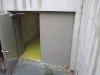 Notausgang von außen, geöffnete Metalltür, betonierte Außenfläche nach der Tür 