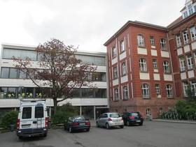 Modernes Gebäude grenzt an einen Altbau mit Eingang in der Mitte der beiden Gebäude