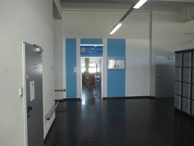 Eingang zur Bahnhofsnmission mit Schriftzug und Symbol über der Tür, links davon Wand mit Tür und rechts davon Schließfächer