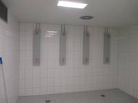 offener Duschbereich mit 4 Duschplätzen in einem gekachelten Raum