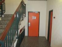 rote Tür in einer weißen Wand, links eine Treppe