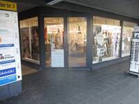 Eine gläserne Ladenfront mit einer zweiflügeligen Türe mit einem senkrechten Haltestange