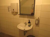 Ein Waschbecken mit einem Spiegel, einem Seifenspender und einem Papierhandtuchhalter