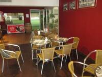 Ein rot gestrichener Gastraum mit runden Tischen und Bistrostühlen.