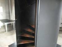Stufen in einem türbreit geöffneten Metallzylinder, der sich mitten im Raum befindet