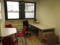 Links an der Wand Tisch mit 3 Stühlen, rechtzs Schreibtisch mit Bürostuhl