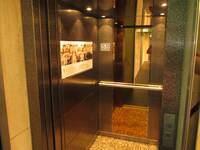 Eine offene Aufzugskabine. an der Rückwand ein Handlauf und ein Spiegel