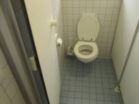 weiße Toilette an einer weiß gekachelten Wand