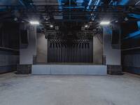 Breite Bühne mit vielfältiger Beleuchtungstechnik und schwarzem Vorhang