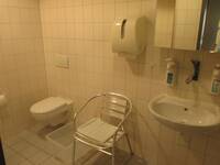 Ein Raum mit einer Toilette, einem Stuhl und einem Waschbecken