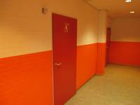 rote einflügelige Tür, in einer Wand die im unteren Teil orange gestrichen ist