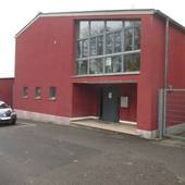 Ein rotes mehrstöckiges Gebäude mit einem zurückgesetztem Eingang