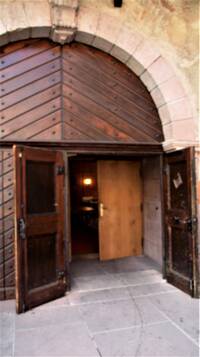 Großes Sandsteinbogen-Portal mit 2-flügliger massiver Holztür, beide Flügel stehen offen