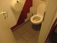Eine weiße Toilette an einer weiß-rot gekachelten Wand