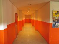 Flur mit Wänden die im unteren Teil orange angestrichen sind, links vorne eine Tür