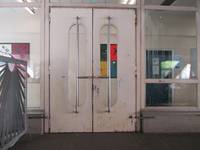 2-flüglige Tür mit senkrechten Griffstange, links und rechts davon breite Glasfronten