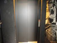 geschlossener Aufzug aus schwarzem Metall, Taster rechts neben der Tür
