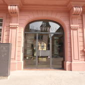 Eingang in das Alte Rathaus unter Rundbogen. Nach hinten versetzte Glastüre. Davor ansteigender Gehweg bis zum Haus.