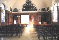 Historischer Saal mit Wandverkleidung aus Holz, großem Kronleuchter und Buntglasfenstern
